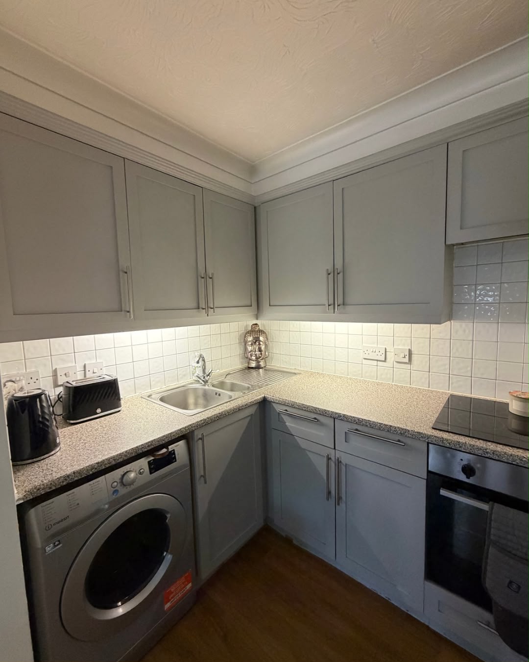 A kitchen we recently cleaned — grey shaker-style cabinets and a white tiled splashback, left spotless